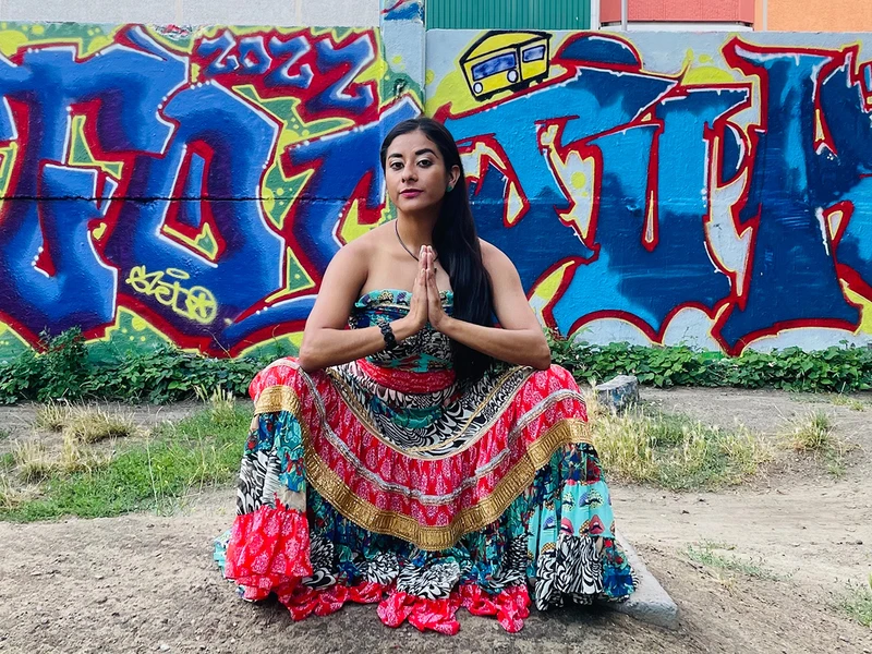 Photo of Rosa Evangelina Beltrán wearing a dress posed in front on a graffiti mural